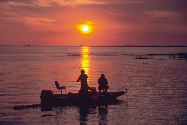 Bass boat with fisherman at sunset